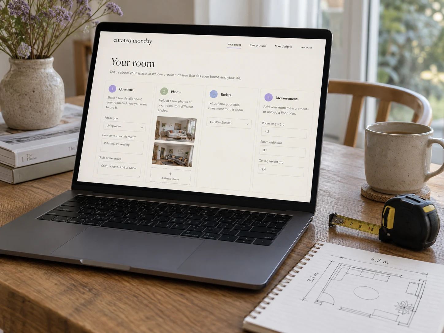 A laptop displaying the client room questionnaire, with a measuring tape and room sketch nearby.